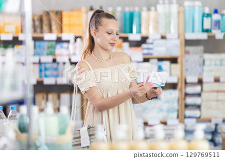 Girl in summer clothes looking for medicine in pharmacy 129769511