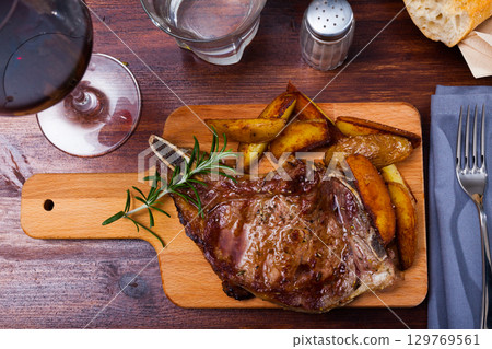 Beef steak with potatoes on a wooden board 129769561