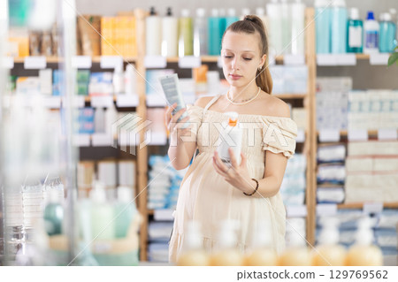 Pregnant woman are busy choosing emollient cream at pharmacy 129769562
