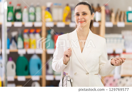 Adult woman chooses household chemicals in store Adult woman chooses household chemicals in store 129769577