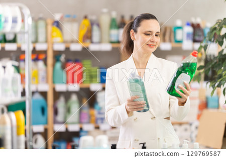 Adult woman chooses dishwashing detergent in store Adult woman chooses dishwashing detergent in store 129769587