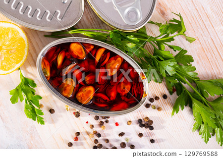 Sea pickled mussels in open tin can served with greens and lemon 129769588