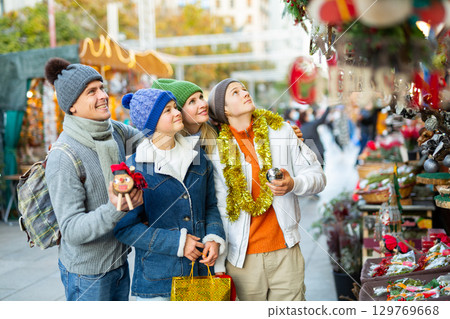 Friendly family chooses Christmas souvenirs and toys Friendly family chooses Christmas souvenirs and toys 129769668