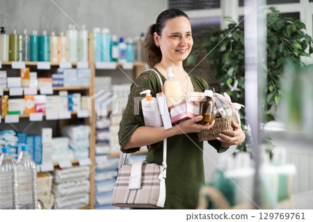 Woman customer in drugstore with full arm of different products 129769761