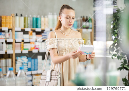 Girl in summer clothes looking for medicine in pharmacy Girl in summer clothes looking for medicine in pharmacy 129769771