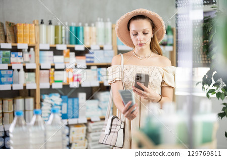 Girl in summer clothes scans code on package of cream to check expiration date Girl in summer clothes scans code on package of cream to check expiration date 129769811
