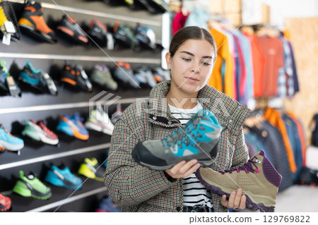 Young girl chooses and buys winter shoes for hiking trips in sports store Young girl chooses and buys winter shoes for hiking trips in sports store 129769822