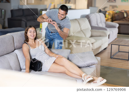 Happy young couple choosing a soft new sofa in furniture store Happy young couple choosing a soft new sofa in furniture store 129769906