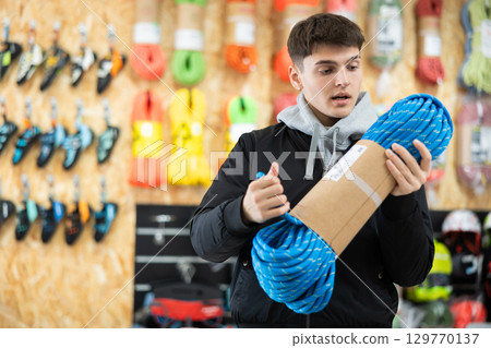 Young man view rope cable for climbing and evaluate its thickness Young man view rope cable for climbing and evaluate its thickness 129770137