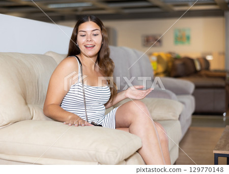 Positive girl is testing new furniture during visiting salon 129770148