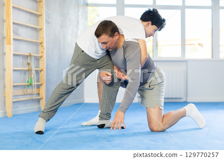 Teenage boy and middle-aged man training throwing method during self-defense courses 129770257