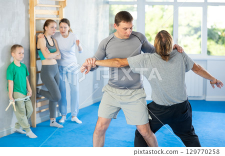 Man with trainer in self-defense training in gym practices trip up opponent during sparring 129770258