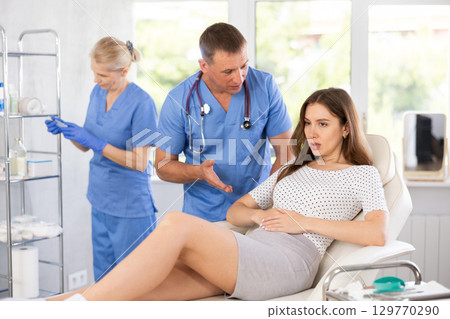 Professional physician listening to female patient health complaints in clinic 129770290