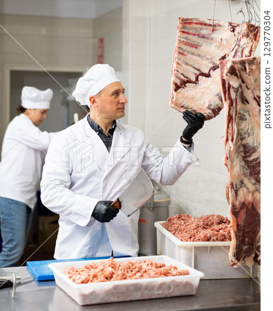 Confident male butcher holding big chunk of beef ribs is prepared in butchery 129770304
