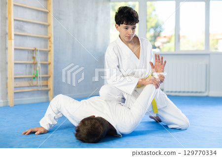 Man and teenage boy train judo fighting techniques 129770334