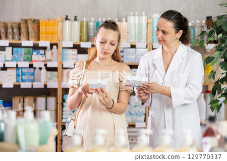 Pregnant woman choosing pills with help of pharmacist 129770337