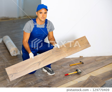 Repairman laying parquet on floor Repairman laying parquet on floor 129770409
