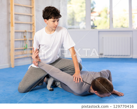 Father teaching his son wrestling or self-defense techniques in gym 129770416