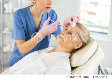 Woman applying rejuvenating treatments by doctor. 129770519