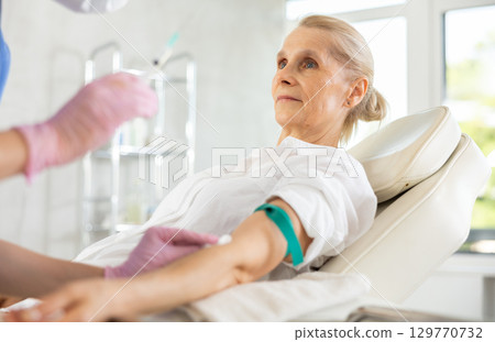 Experienced doctor making intravenous injection to senior woman 129770732