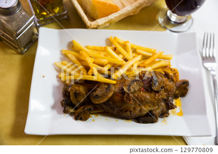 Oven baked pork knuckle with french fries and mushrooms 129770809