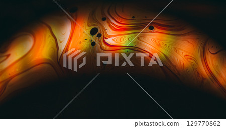 Glow arch blur. Rainbow soap flow. Orange red green ink round light lens on black background. Color blending liquid abstract texture. Glow arch blur. Rainbow soap flow. Orange red green ink round light lens on black background. Color blending liquid abstract texture. 129770862