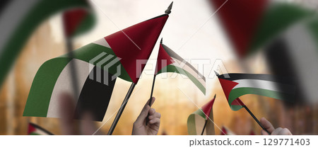 Palestine flags in their hands on a blurred urban background 129771403
