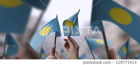 Palau flags in their hands on a blurred urban background 129771413