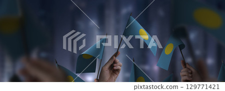 Palau flags in their hands on a blurred urban background 129771421