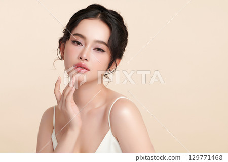 A beautiful young Asian woman with clean, fresh skin against a beige background. Skincare, facial treatment, cosmetology, beauty, and spa. An elegant portrait of an Asian woman. A beautiful young Asian woman with clean, fresh skin against a beige background. Skincare, facial treatment, cosmetology, beauty, and spa. An elegant portrait of an Asian woman. 129771468