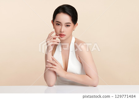 A beautiful young Asian woman with clean, fresh skin against a beige background. Skincare, facial treatment, cosmetology, beauty, and spa. An elegant portrait of an Asian woman. A beautiful young Asian woman with clean, fresh skin against a beige background. Skincare, facial treatment, cosmetology, beauty, and spa. An elegant portrait of an Asian woman. 129771484