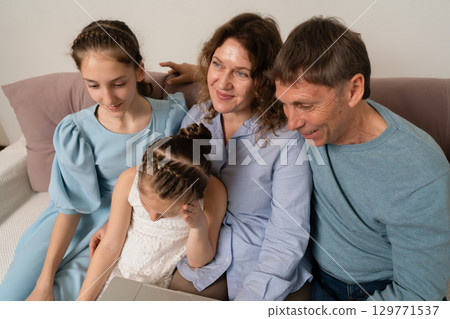 Family laptop children indoors watches content together in living room during daytime, bonding and sharing time. Family laptop children indoors watches content together in living room during daytime, bonding and sharing time. 129771537