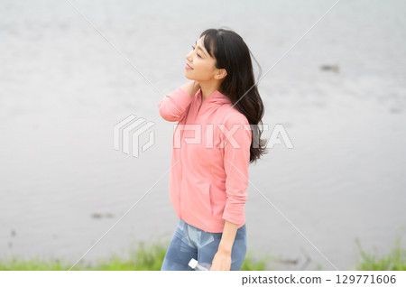 A woman standing by the water in a park A woman standing by the water in a park 129771606