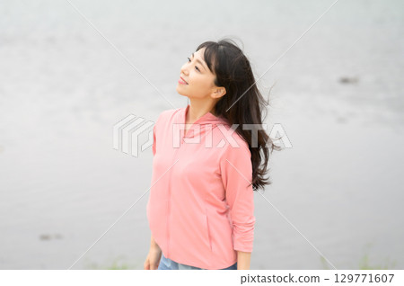 一名女子站在公園的水邊 129771607