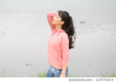 A woman standing by the water in a park A woman standing by the water in a park 129771614