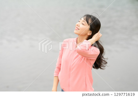 一名女子站在公園的水邊 129771619