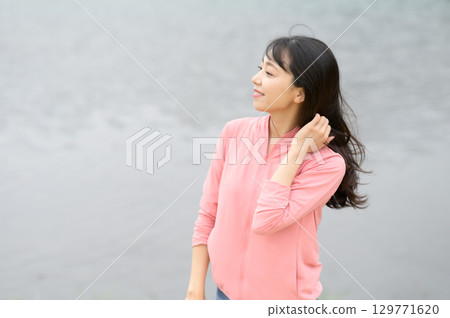 A woman standing by the water in a park A woman standing by the water in a park 129771620