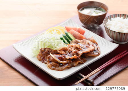 A freshly cooked piping hot pork shogayaki set meal featuring steaming juicy pork and cabbage for a Japanese lunch. 129772089