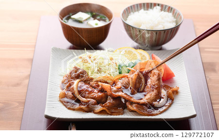 A freshly cooked piping hot pork shogayaki set meal featuring steaming juicy pork and cabbage for a Japanese lunch. 129772107