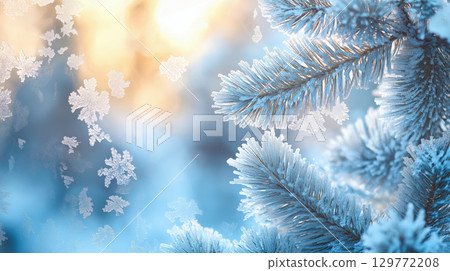 Christmas frosty pine tree branches with ice crystals and falling snowflakes on blurred blue and warm background, winter scene 129772208