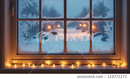 Christmas frosty window with glowing garland and snow-covered street outside in evening light. Winter home coziness. 129772272