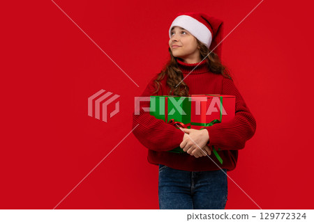 Girl in Santa hat holds Christmas gifts Girl in Santa hat holds Christmas gifts 129772324