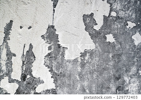 Closeup view of heavily textured white painted concrete wall. The surface is old and worn with peeling paint. Abstract background Closeup view of heavily textured white painted concrete wall. The surface is old and worn with peeling paint. Abstract background 129772403