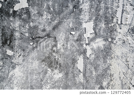 Closeup view of heavily textured white painted concrete wall. The surface is old and worn with peeling paint. Abstract background 129772405