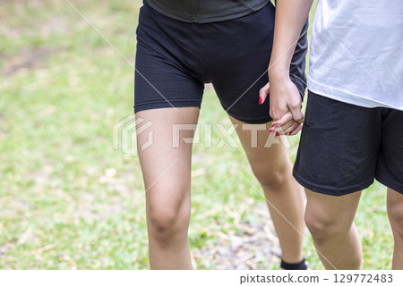 Couple in a sporty outfit holding hands while walking in a public park outdoors. Concept of a Healthy active lifestyle 129772483