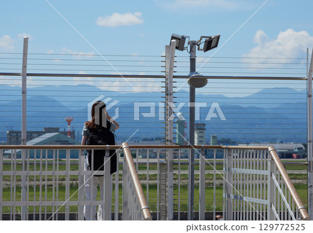A female tourist looking at the scenery from the observation deck at Komatsu Airport on a summer day 129772525