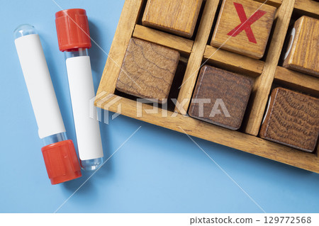 Closeup view of an empty test tube with a wooden tic tac toe game on a blue background. Mockup or Copy space. Concept of healthcare and medicine Closeup view of an empty test tube with a wooden tic tac toe game on a blue background. Mockup or Copy space. Concept of healthcare and medicine 129772568