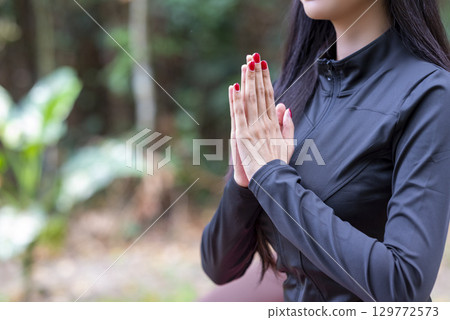 Woman in a sporty outfit is relaxing and meditating zen-like on a fitness mat in a public park outdoors. Concept of a Healthy active lifestyle Woman in a sporty outfit is relaxing and meditating zen-like on a fitness mat in a public park outdoors. Concept of a Healthy active lifestyle 129772573