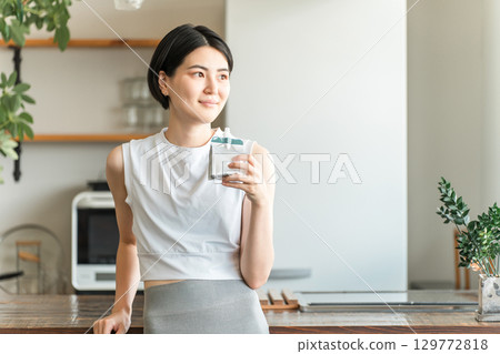 一位身穿運動服的亞洲年輕女子正在喝果凍,並以營養補充果凍補充能量 一位身穿運動服的亞洲年輕女子正在喝果凍,並以營養補充果凍補充能量 129772818