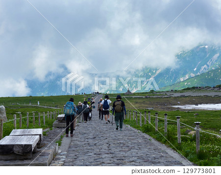 Summer tourist attraction, scenery of the summit of Mt. Murodo on the Tateyama Kurobe Alpine Route, and people sightseeing Summer tourist attraction, scenery of the summit of Mt. Murodo on the Tateyama Kurobe Alpine Route, and people sightseeing 129773801